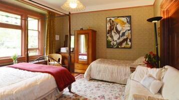 A room with two beds, a wooden cabinet, a painting, and a lamp.