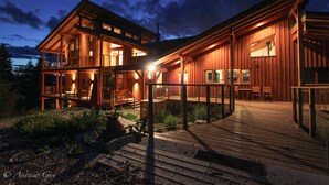 Una cabaña de madera con terraza y zona de estar al aire libre, rodeada de follaje.