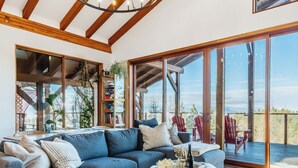 Un salón amplio con un sofá seccional grande, una chimenea y vistas al exterior a través de grandes puertas corredizas de cristal.