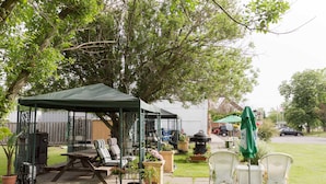 Un patio couvert avec des meubles d’extérieur, un barbecue et des plantes en pot.