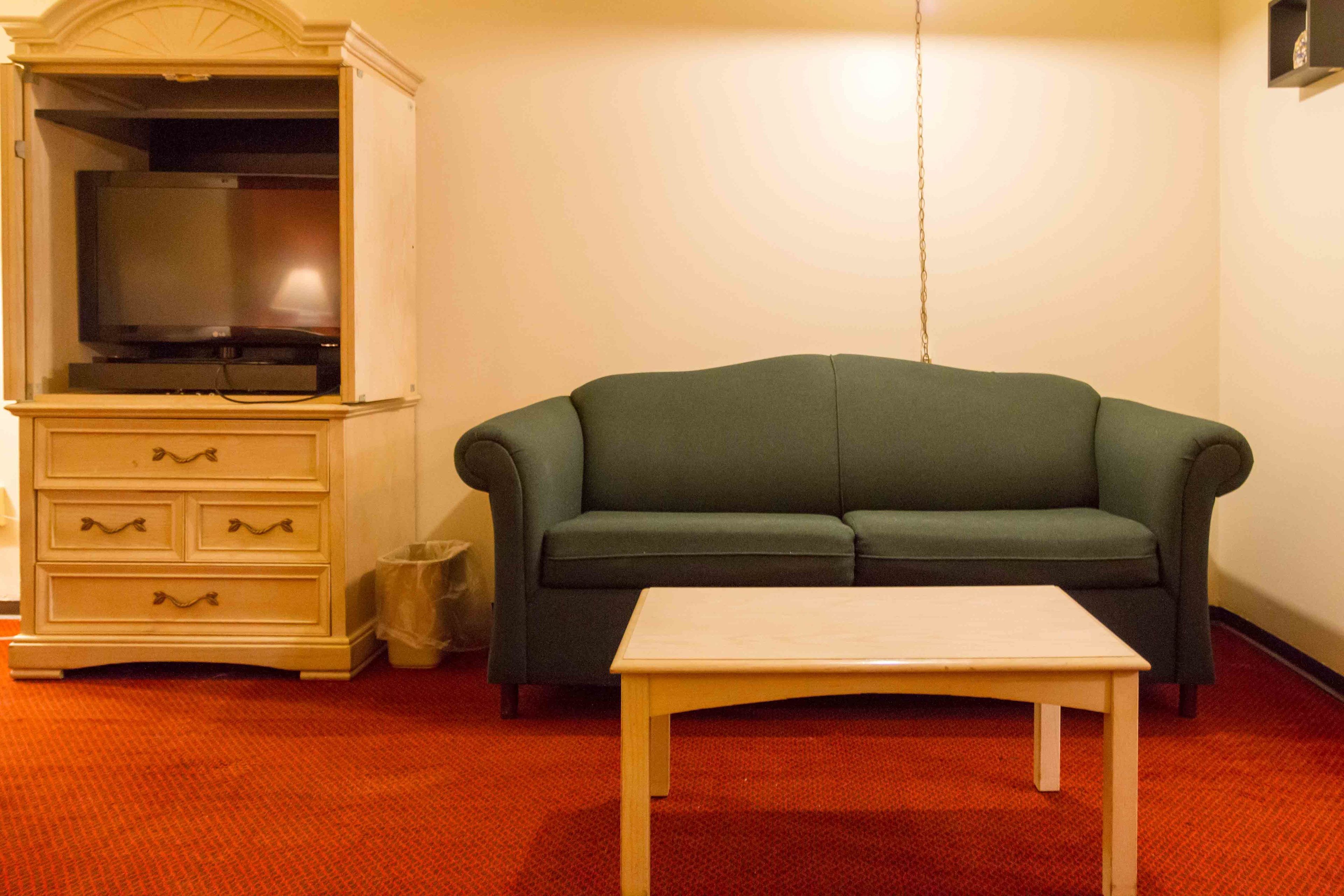 A living room with a green sofa, a white table, and a wooden cabinet with drawers.