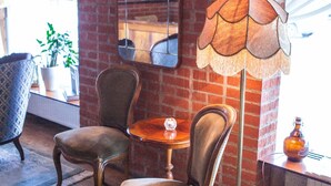 Une pièce comprenant deux fauteuils rembourrés, une petite table ronde, un lampadaire et un miroir au mur.