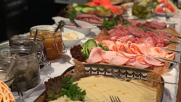 A buffet table with various food items including meats, cheeses, and fruits.