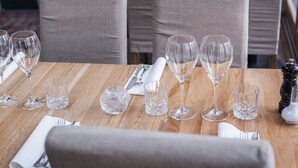 Une table à manger dressée avec des verres à vin, des verres à eau et un salier et un poivrier.