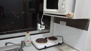 Une cuisine équipée d’un four à micro-ondes, d’une cuisinière, d’un évier et d’une bouteille de liquide vaisselle Fairy.
