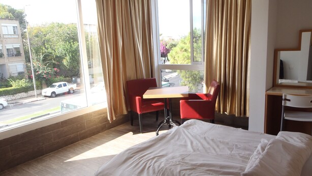 Une chambre d’hôtel avec un lit, un bureau et une chaise près d’une fenêtre avec des rideaux.