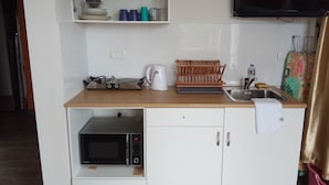 Une petite cuisine équipée d’un four à micro-ondes, d’une bouilloire et d’un petit évier.