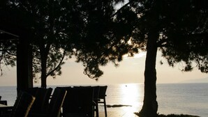 A terrace with chairs and tables, overlooking a body of water during sunset.