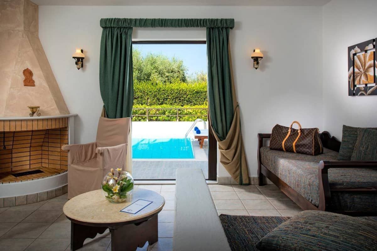A room with a fireplace, a pool view, a sofa, and a table with a vase.