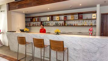 A bar area with a marble counter, wooden chairs, and a variety of liquor bottles.