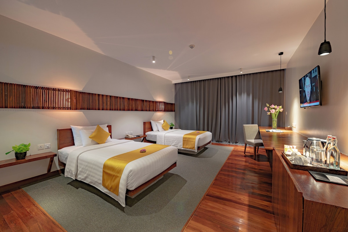 Une chambre d’hôtel moderne équipée de deux lits, d’un bureau, d’une chaise, d’une télévision et d’un coin repas.
