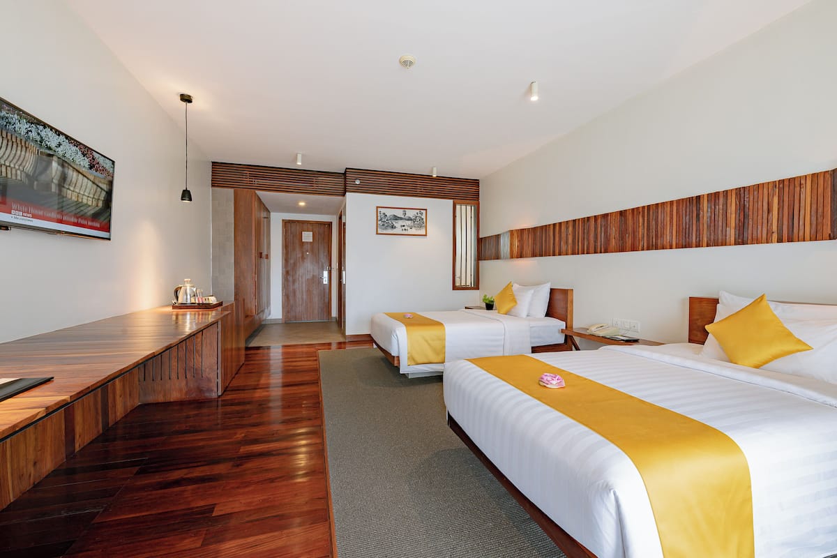 Een hotelkamer met twee bedden, een houten bureau en een klein tafeltje met een waterkoker.