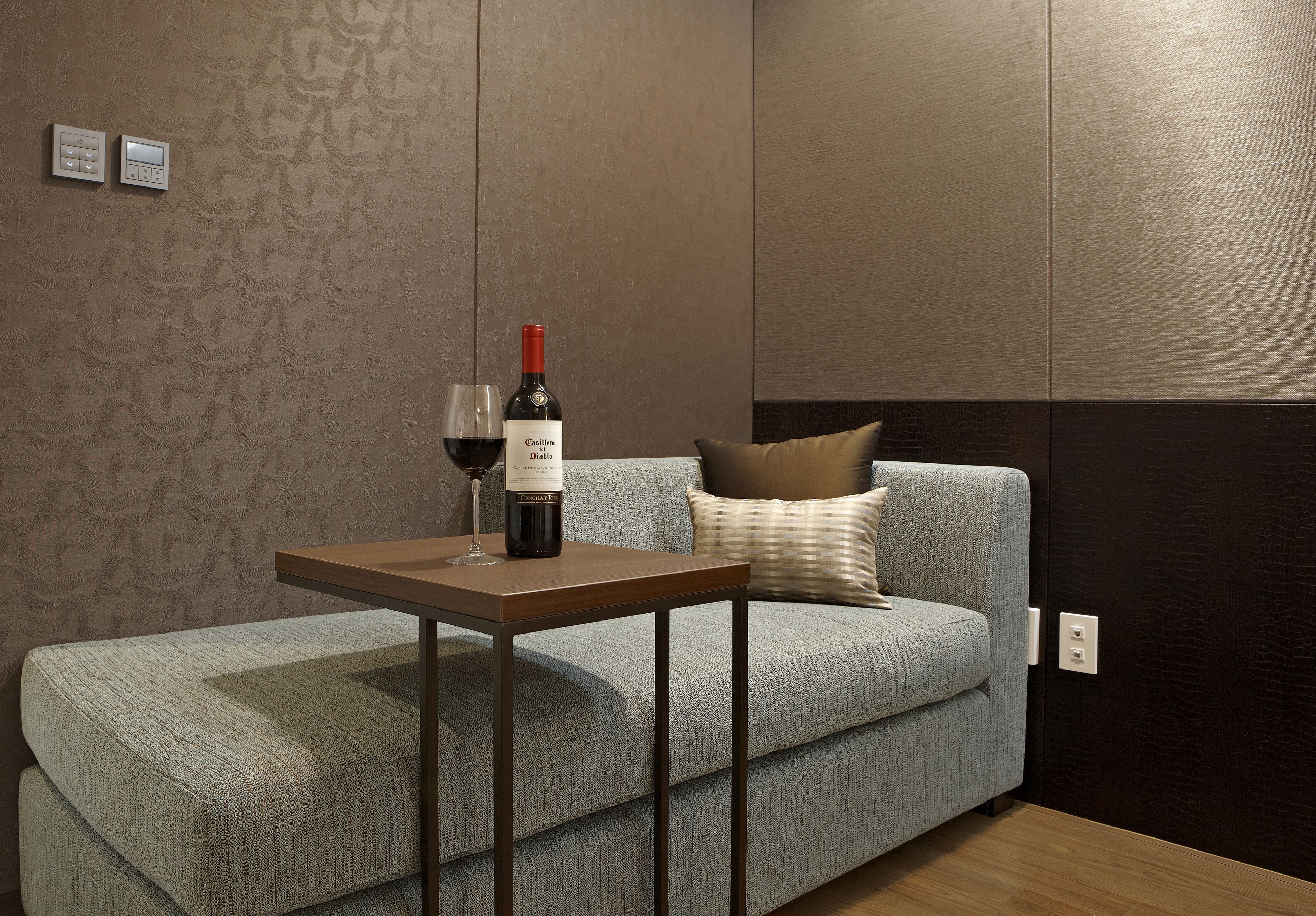 A modern living room with a grey sofa, a wooden coffee table, and a wine bottle.