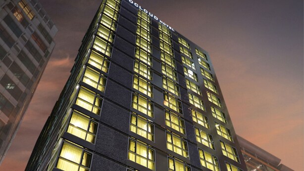 Un edificio de hotel alto con ventanas iluminadas y un cartel que dice "Colour Hotel".