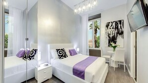 Habitación de hotel moderna con dos camas, un escritorio, una silla, un televisor y un ventanal con vistas a palmeras.