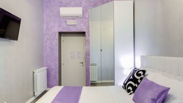 A bedroom with a bed, a TV, a wardrobe, and a door.