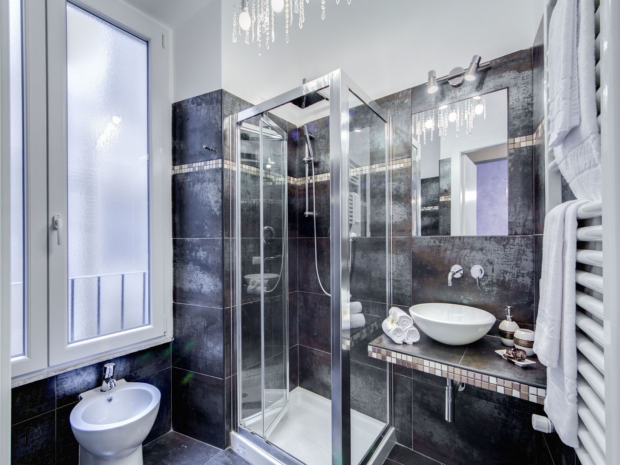 A modern bathroom with a glass-enclosed shower, a white sink, and a large mirror.