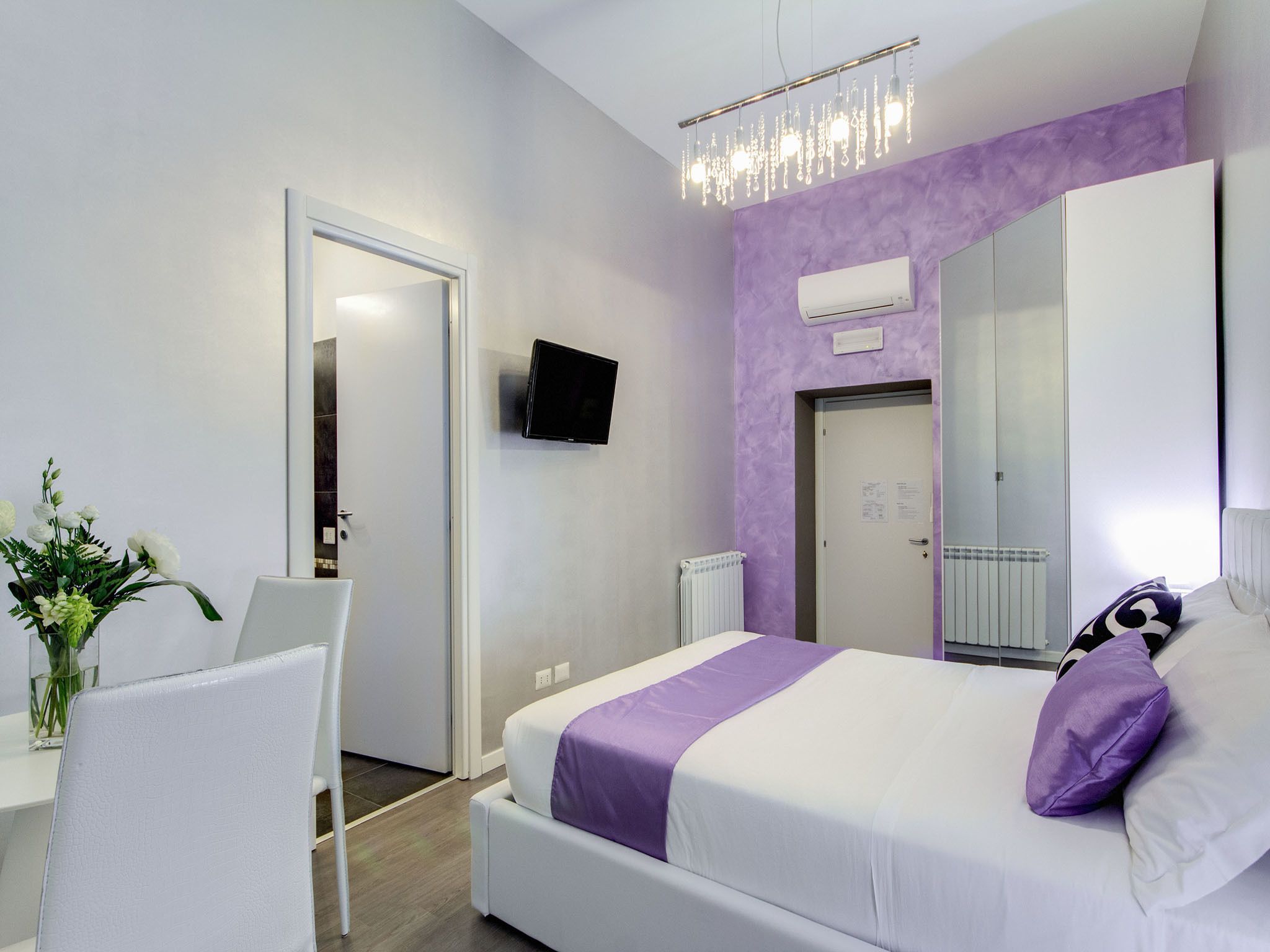 Ein modernes Schlafzimmer mit Bett, Schreibtisch, Stuhl, Spiegel und Fernseher.