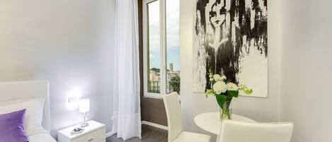 Une chambre d’hôtel moderne, équipée d’un lit, d’une table de chevet, d’une lampe et offrant une vue sur la ville grâce à une grande fenêtre.