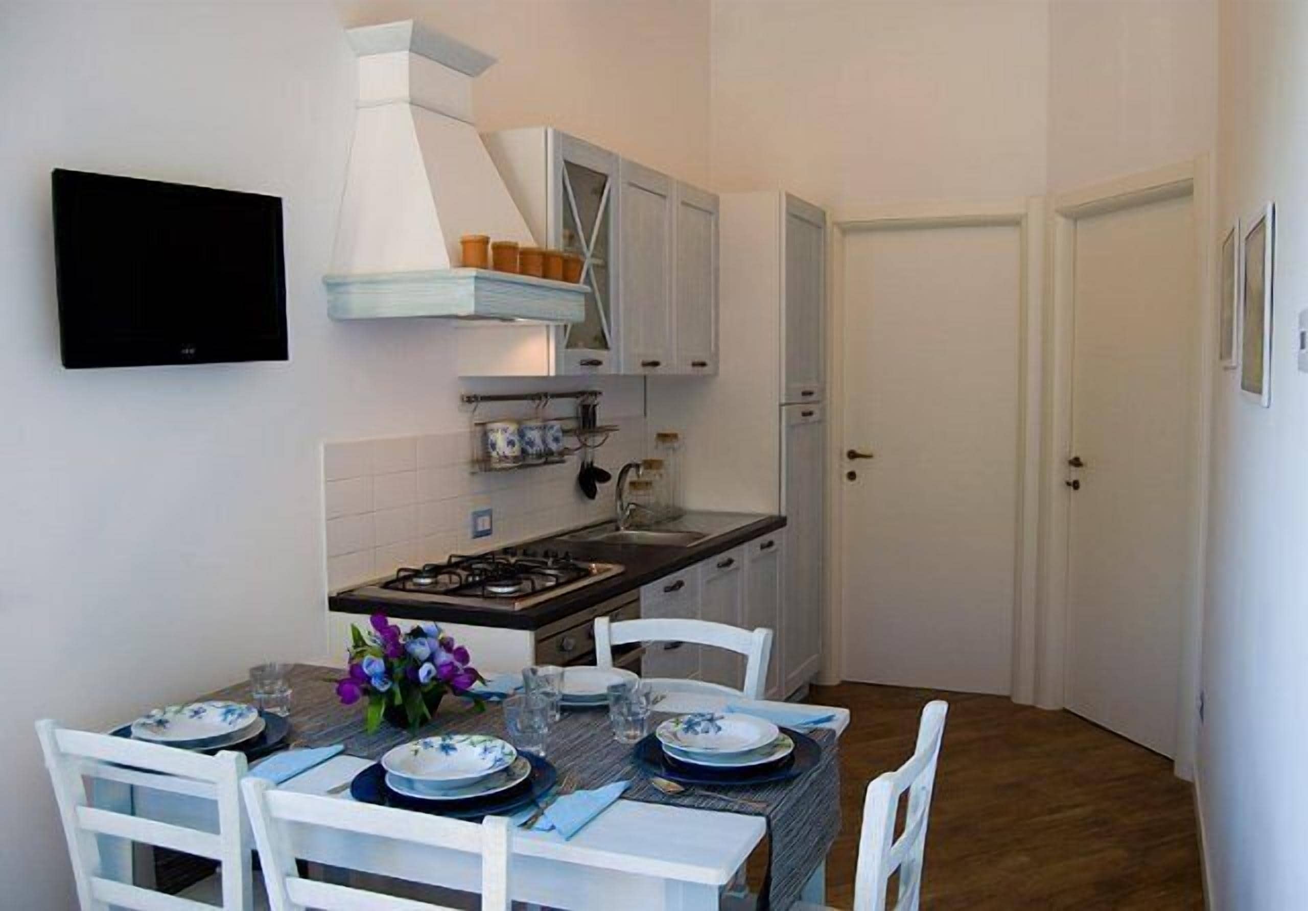 A compact kitchen with white cabinets, a gas stove, and a dining table set for four.