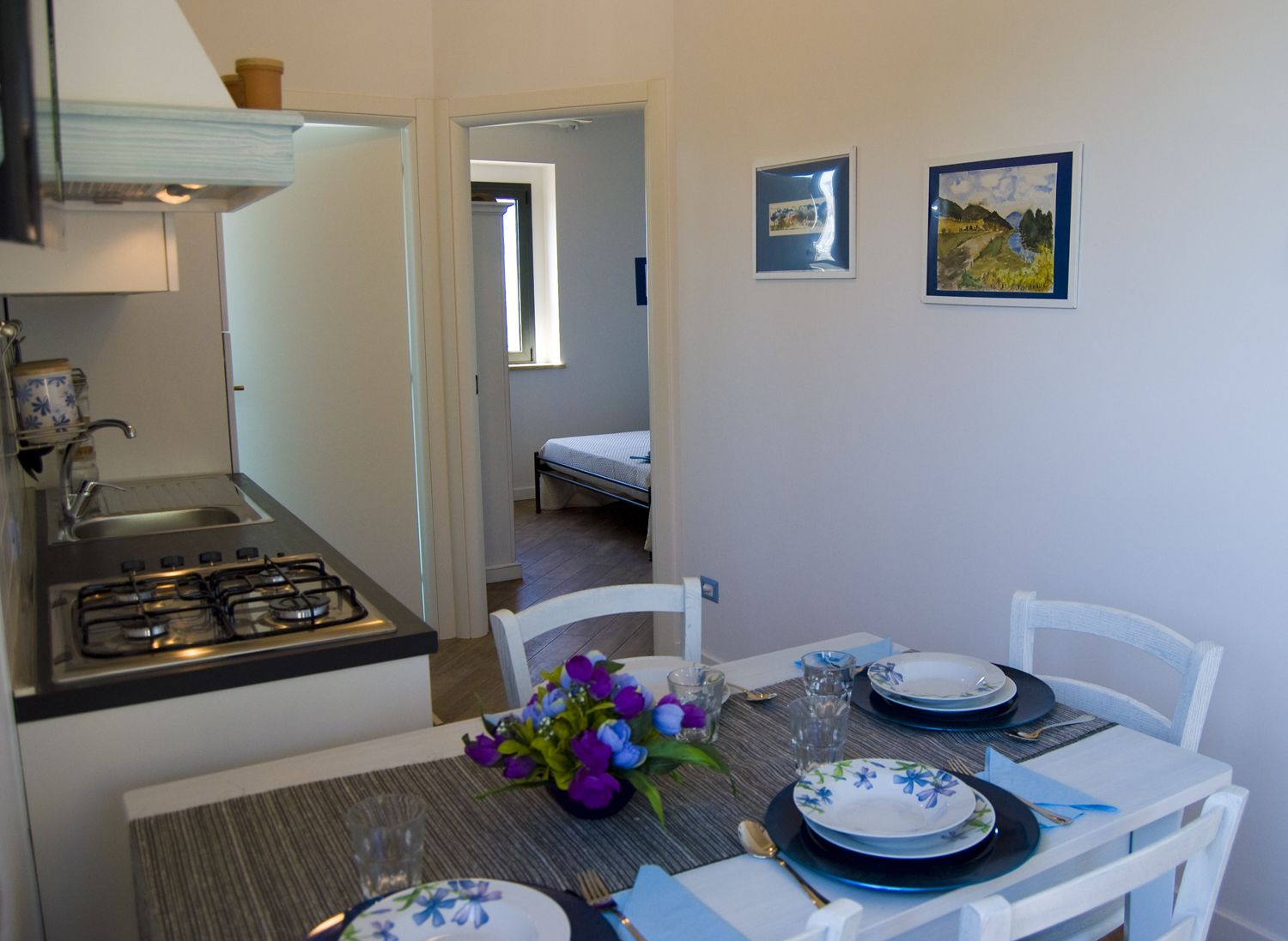 A compact kitchen with a gas stove, a sink, and a dining area with a table set for two.