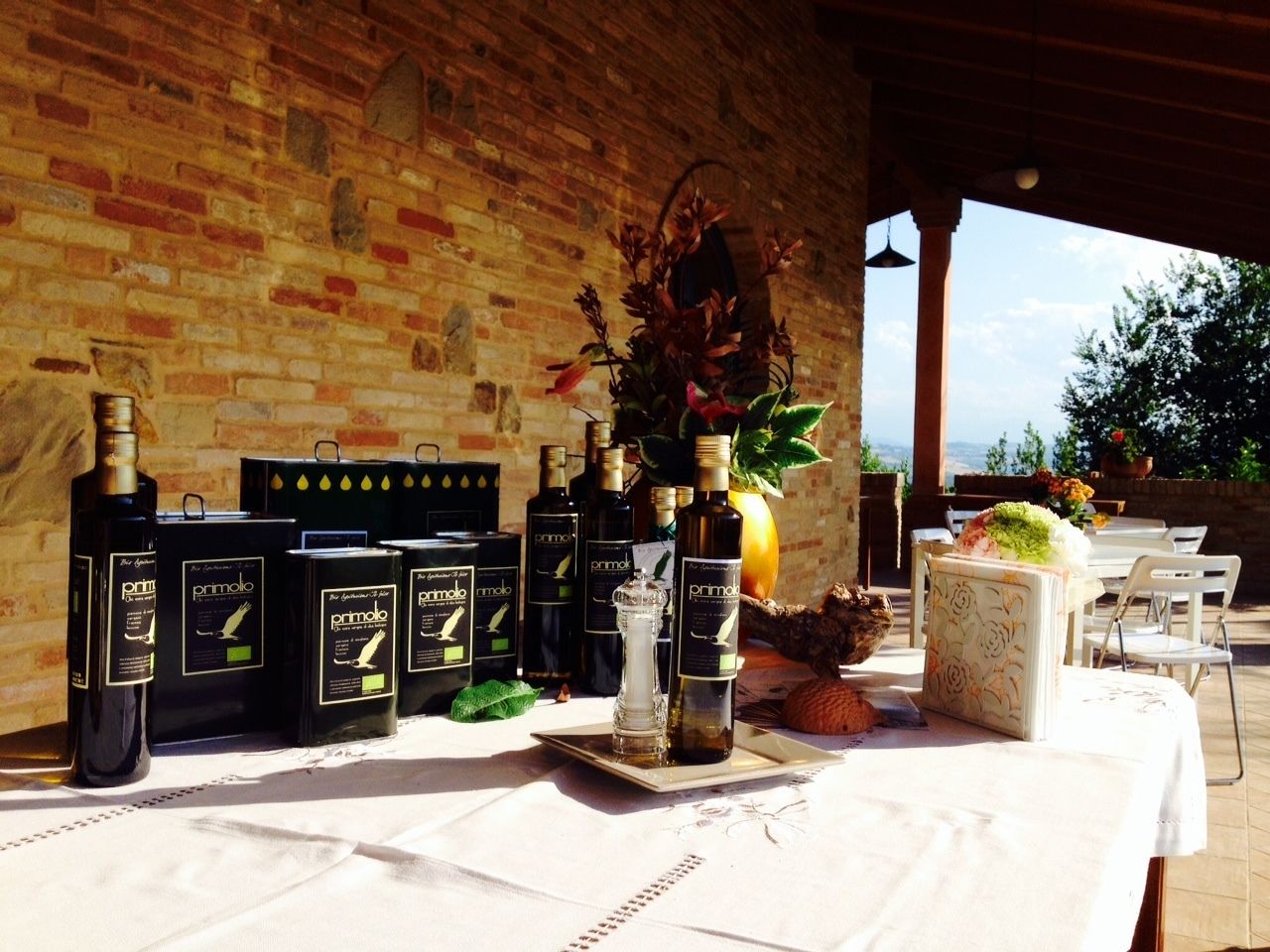 A table with bottles of Prinomolo wine, a glass vase with flowers, and a decorative box with a floral pattern.