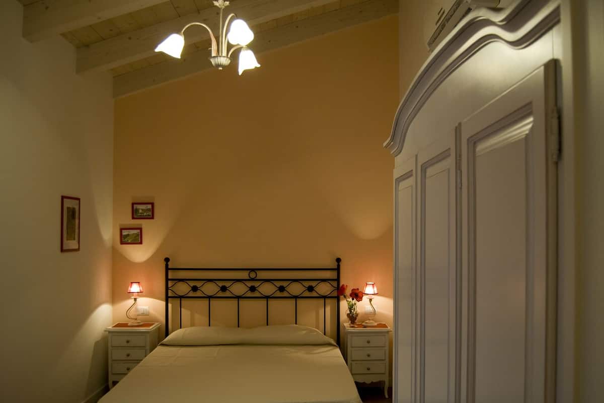 Une chambre à coucher comprenant un lit, deux tables de chevet avec des lampes, un lustre et une armoire.
