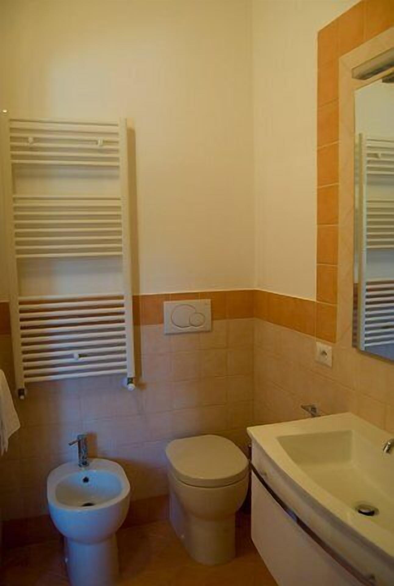 A small bathroom with a bidet, toilet, and sink.