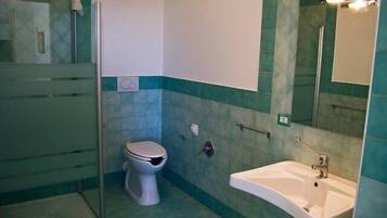 Une salle de bain avec des toilettes, un lavabo et une douche.