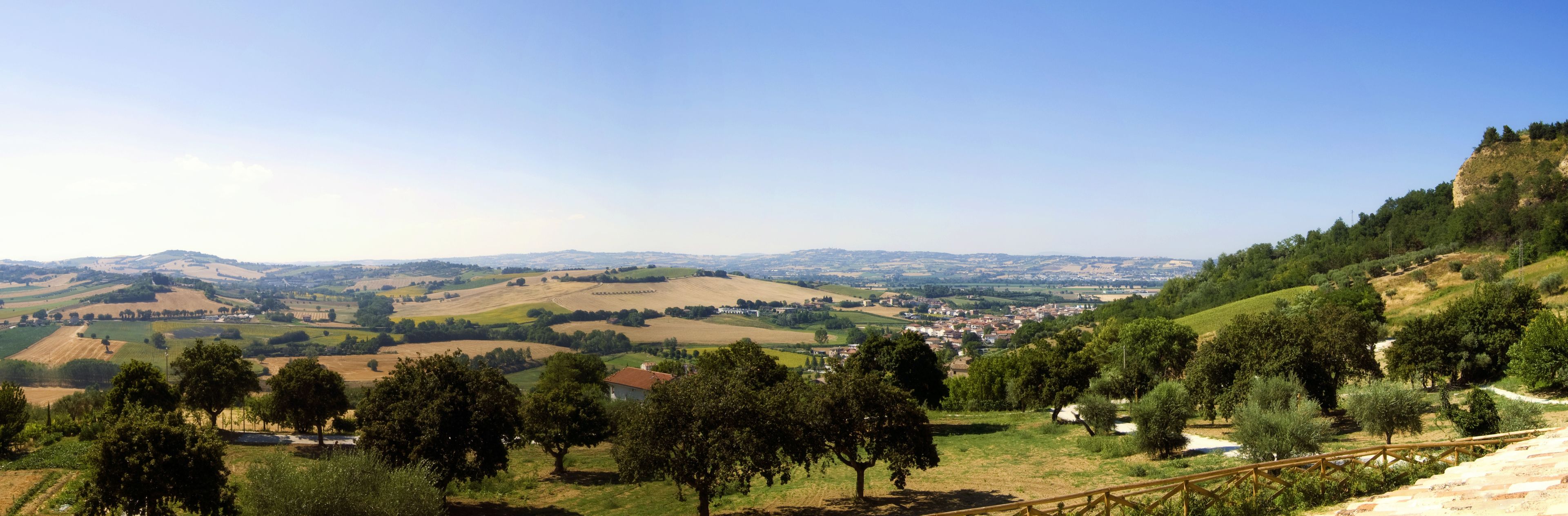 A rural landscape with rolling hills, a small town, and scattered trees.