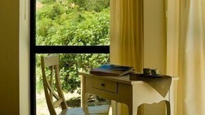 Una habitación con cama, un escritorio y una silla, y una ventana con cortinas.