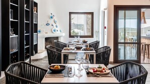 Un comedor moderno con una mesa larga, sillas negras y lámparas colgantes.