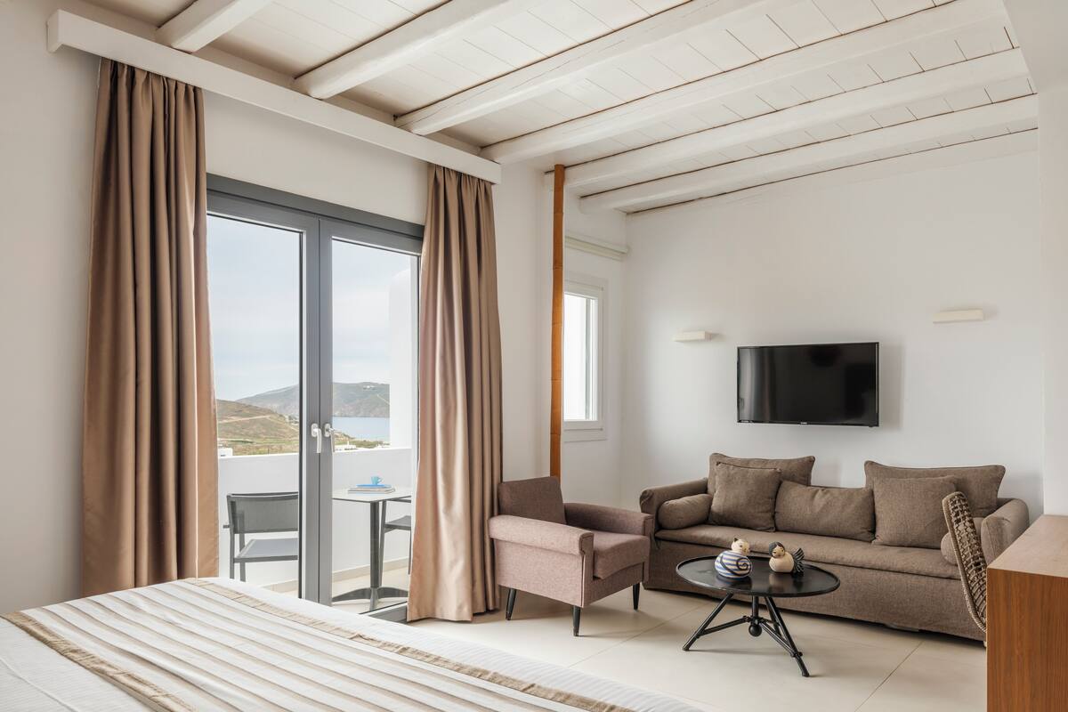 A hotel room with a bed, a sofa, a coffee table, and a TV.