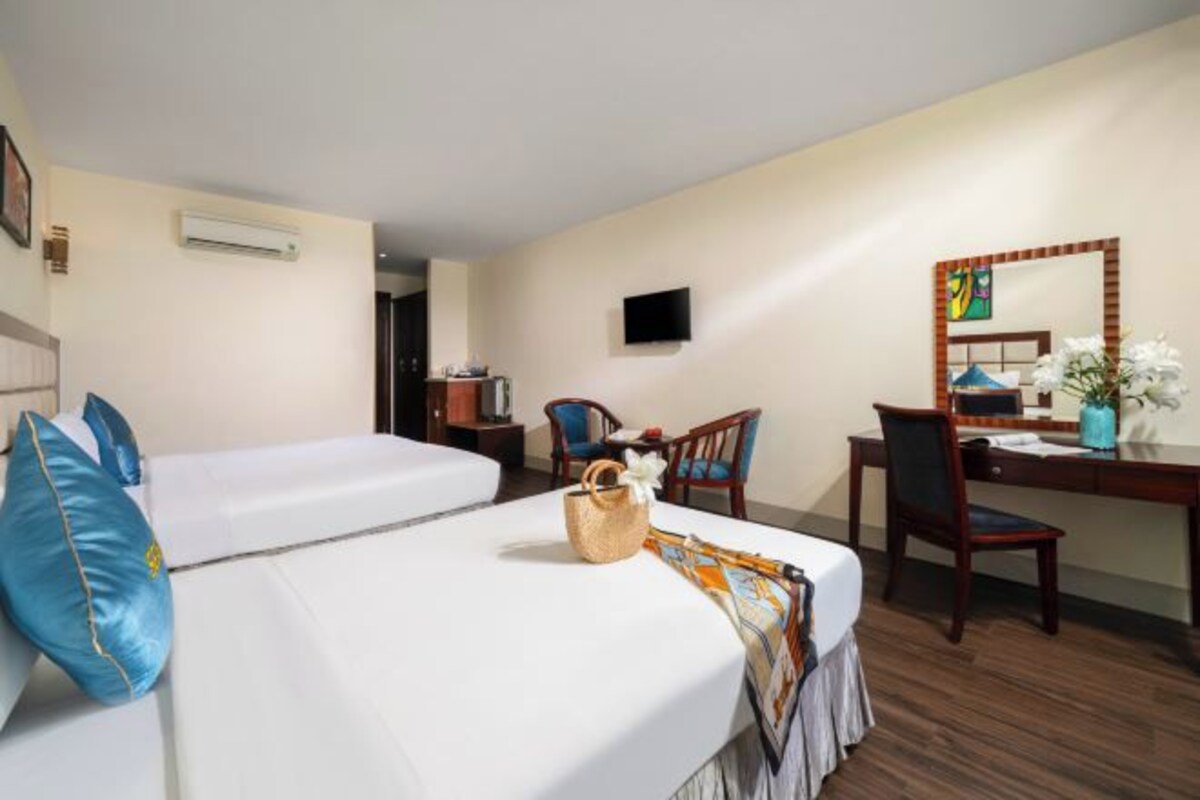 A hotel room with two beds, a desk, a chair, a TV, and a mirror.