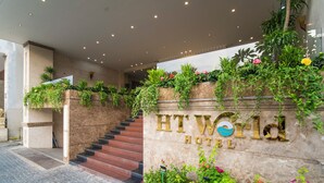 A hotel entrance with a stone wall, stairs, and lush greenery. - Sea Front Hotel (Da Nang)