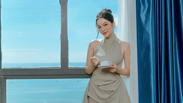 A person standing by a window with a view of the sea. - Sea Front Hotel (Da Nang)