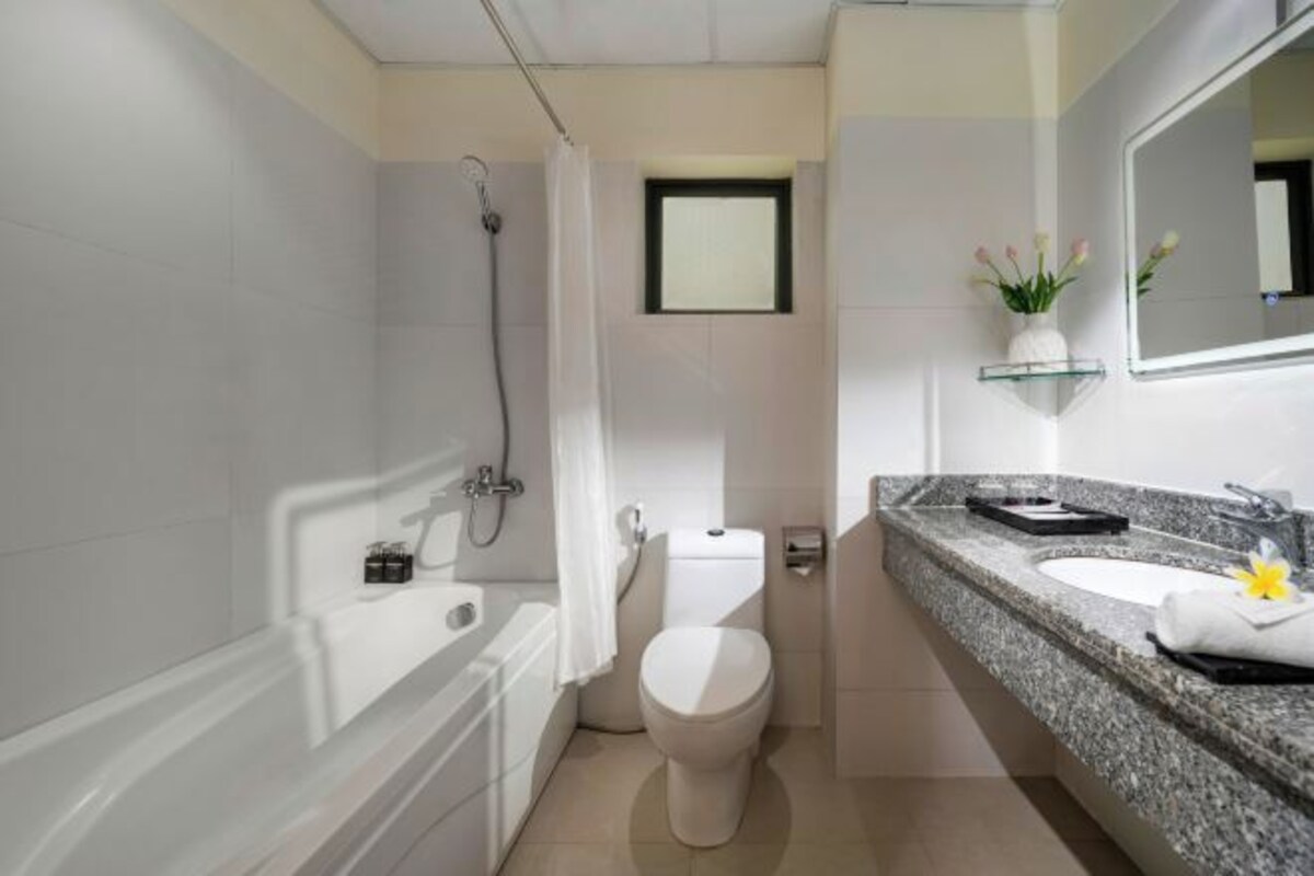 A modern bathroom with a bathtub, toilet, and granite countertop sink.