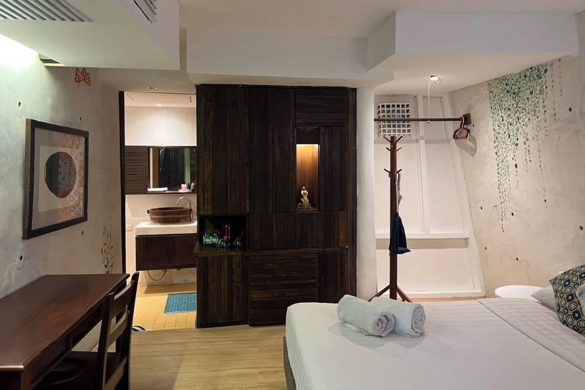 A modern bedroom with a wooden bed, a bedside table, a desk, and a large mirror.