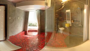 Un baño moderno con cabina de ducha de vidrio, suelo de baldosas rojas y un inodoro a la vista.