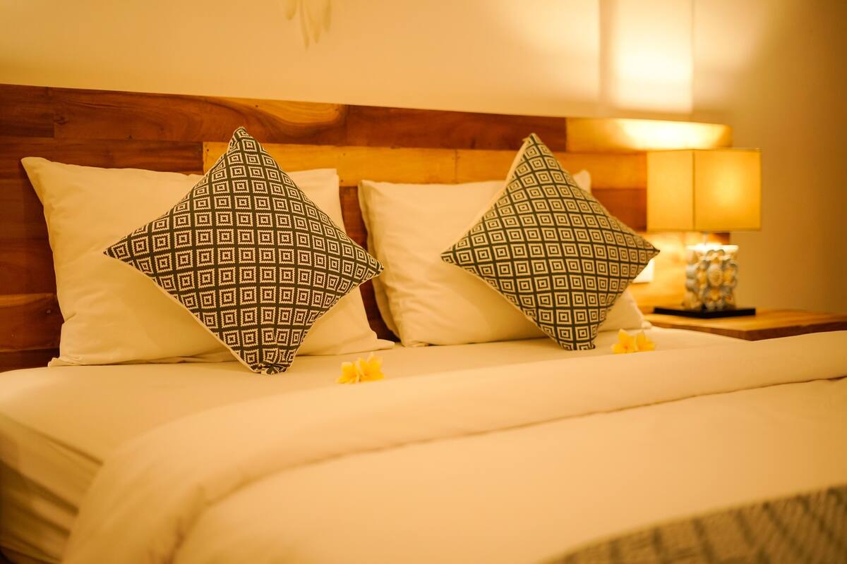 A bed with patterned pillows, a bedside lamp, and a small decorative item on the nightstand.