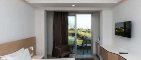 A modern hotel room with a bed, a chair, a TV, and a balcony with a view.