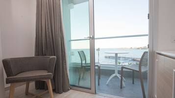Un balcón con vista al mar, una silla y una mesa.