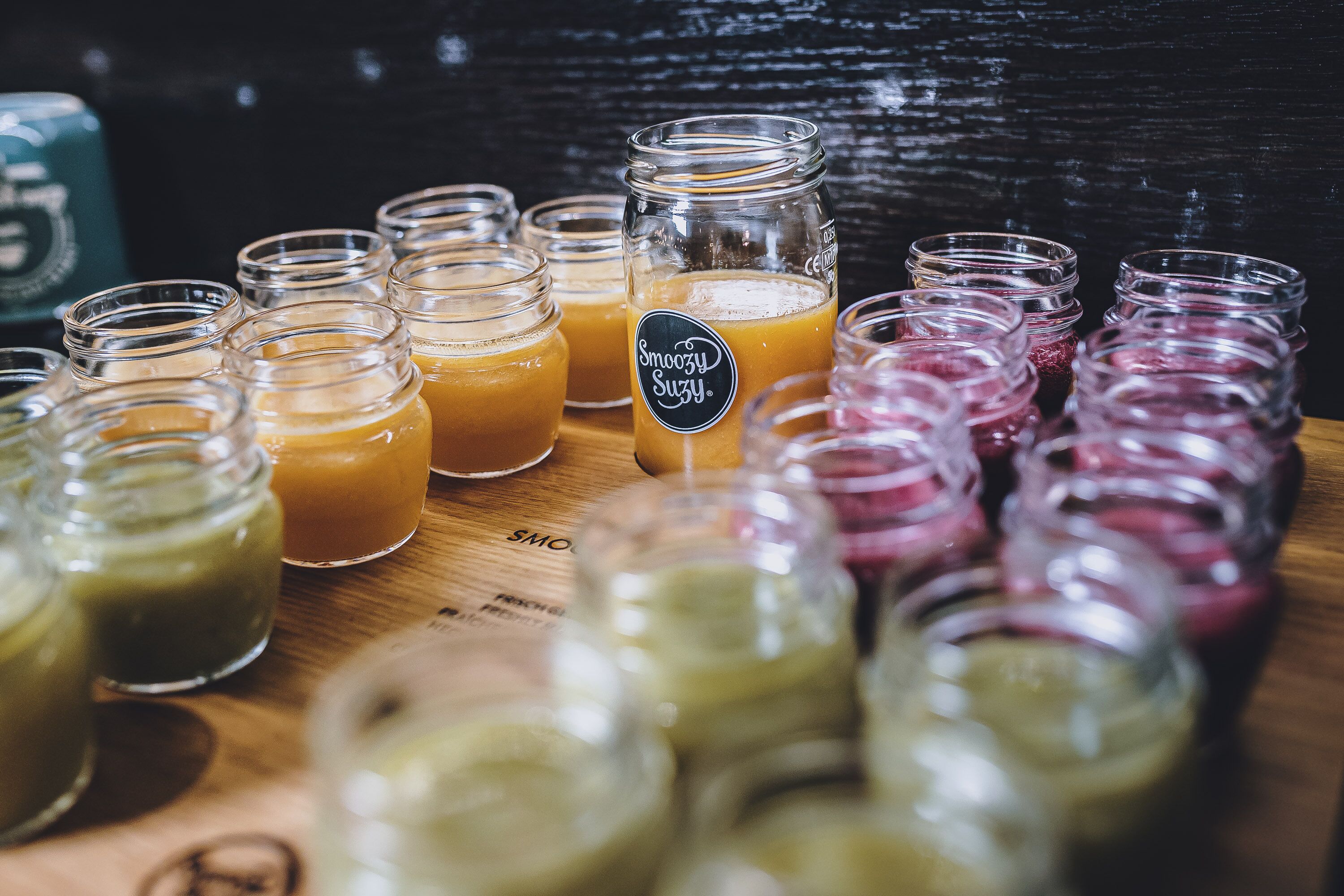 Variedad de bebidas en frascos de vidrio sobre una superficie de madera.