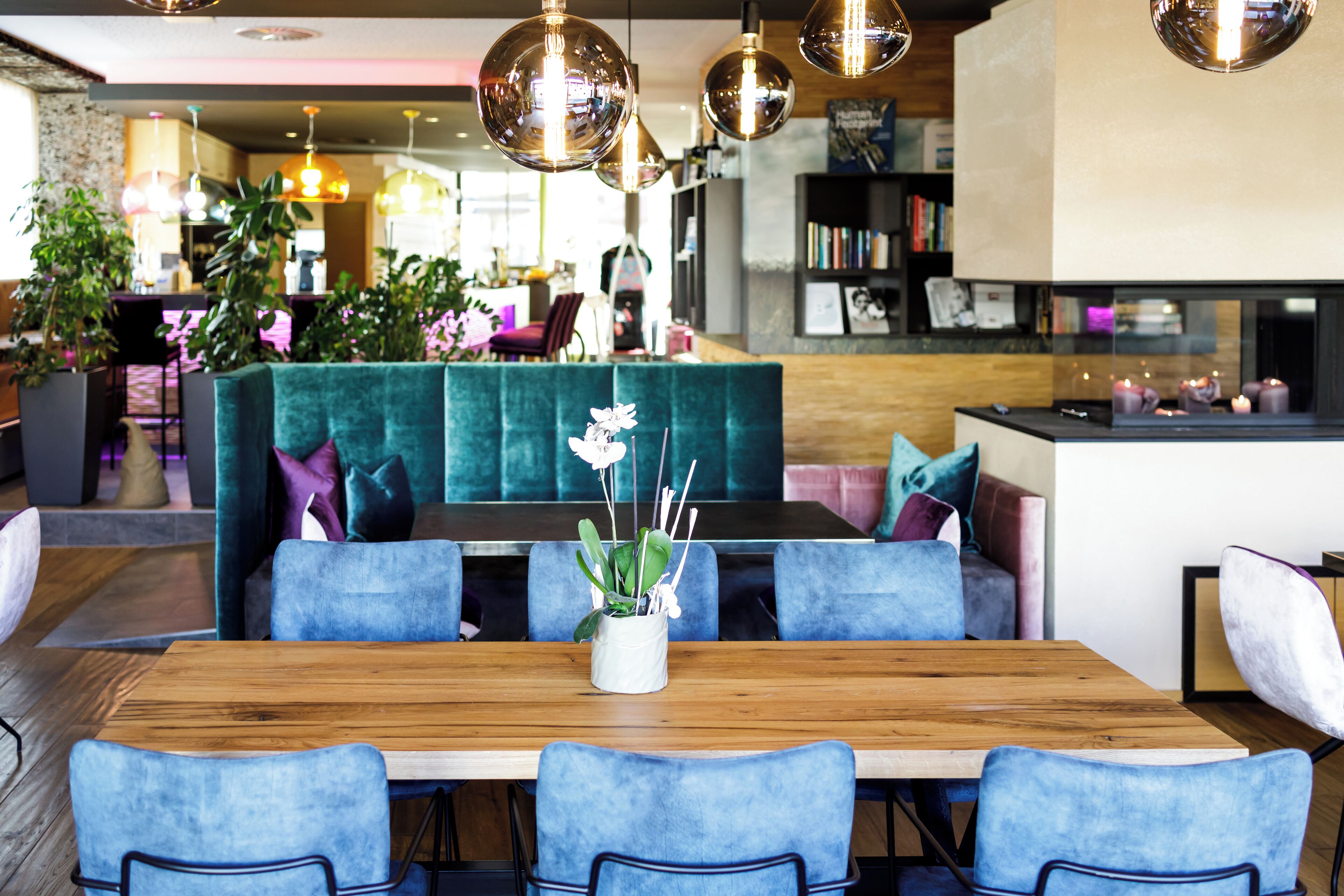 Et moderne spiseområde med et træbord, blå polstrede stole og en teal sofa.