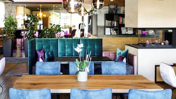 Et moderne spiseområde med et træbord, blå polstrede stole og en teal sofa.