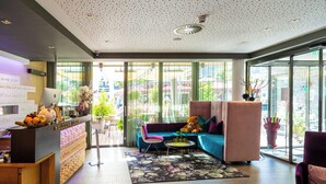 A modern reception area with a wooden desk, a sofa, and a chair. - Lederer Boutique Hotel  (Kaprun)