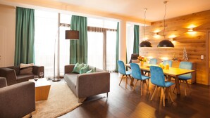 A modern living room with a sofa, chairs, a coffee table, and a dining area with a table and chairs. - Lederer Boutique Hotel  (Kaprun)