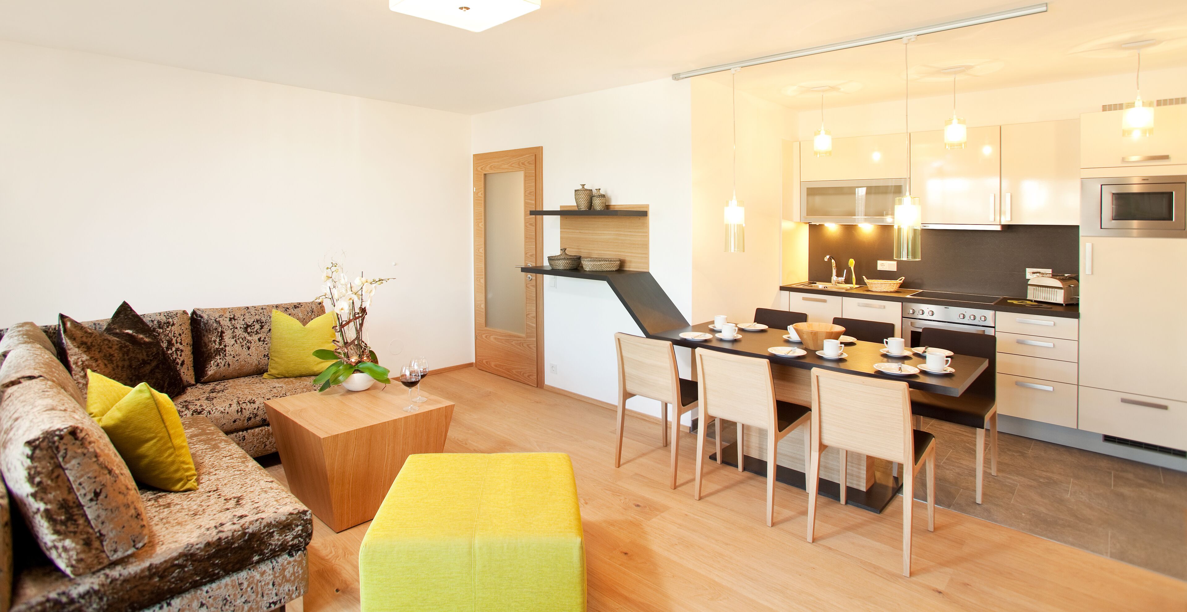 Ein modernes Wohnzimmer mit Sofa, Couchtisch und Essbereich mit Stühlen und Tisch.