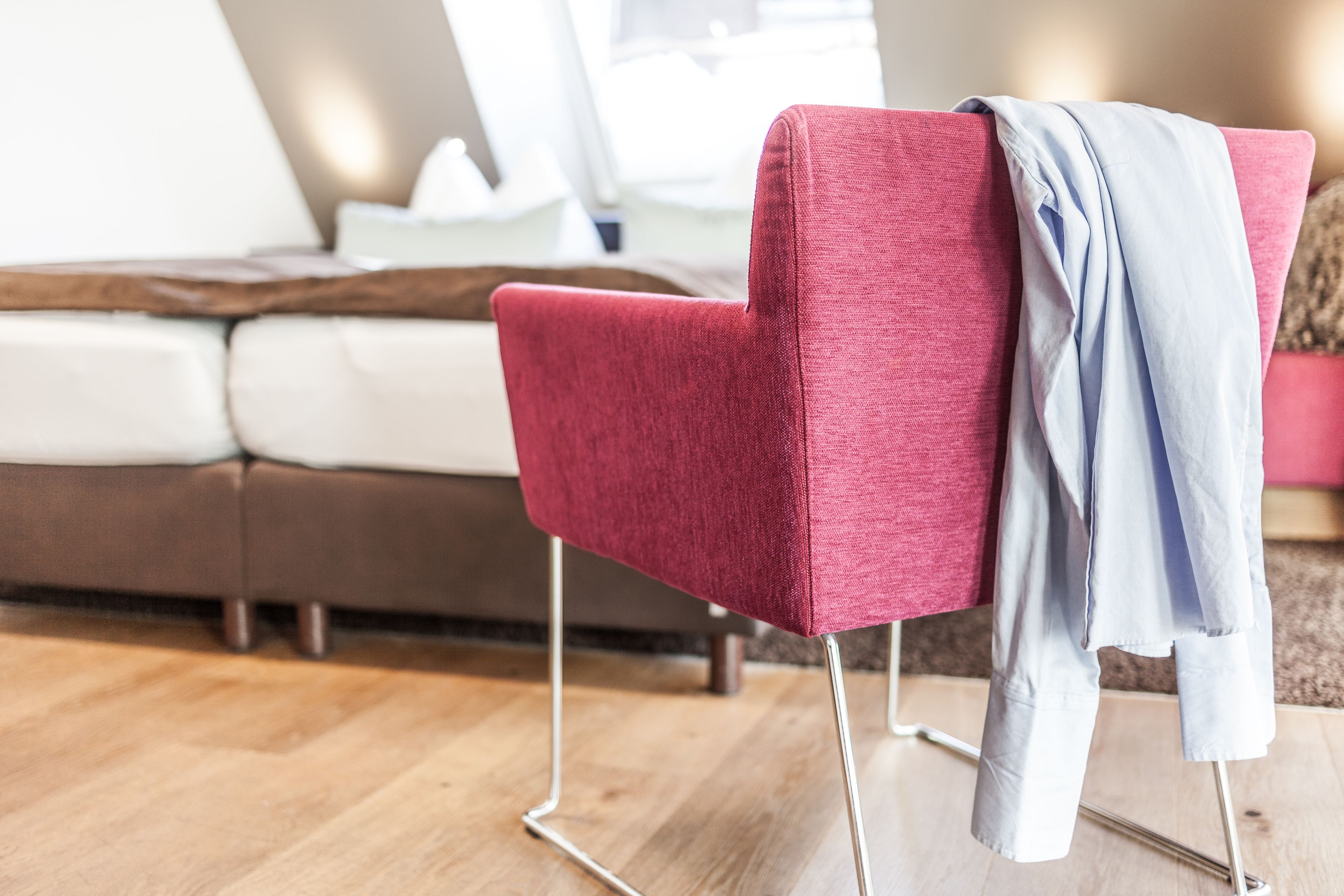 Una silla roja con patas de metal y una chaqueta azul claro colgada sobre ella.