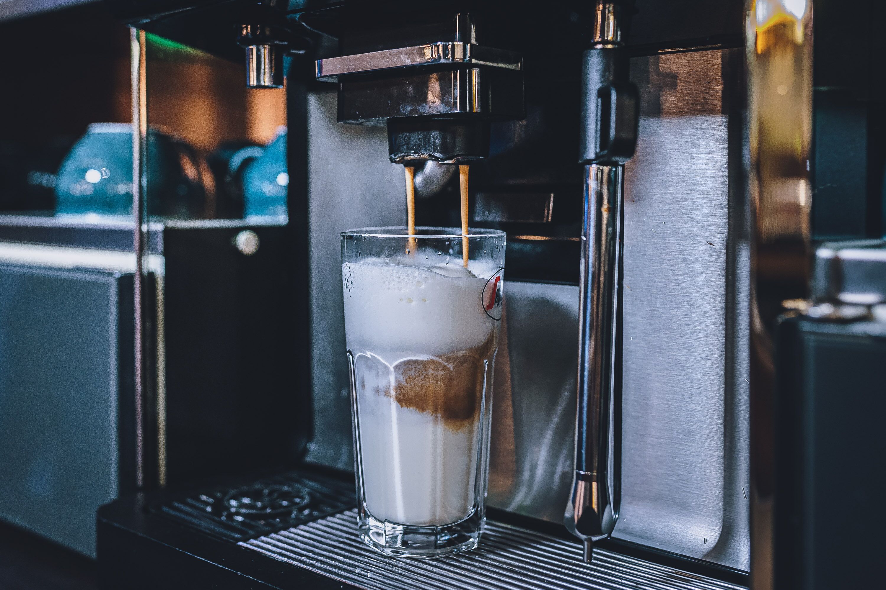 A coffee machine dispensing coffee into a glass.